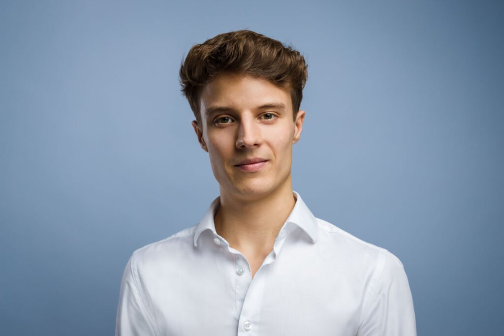 Profesjonalny headshot mężczyzny w białej koszuli na jasnym tle – idealne zdjęcie do LinkedIn i CV.