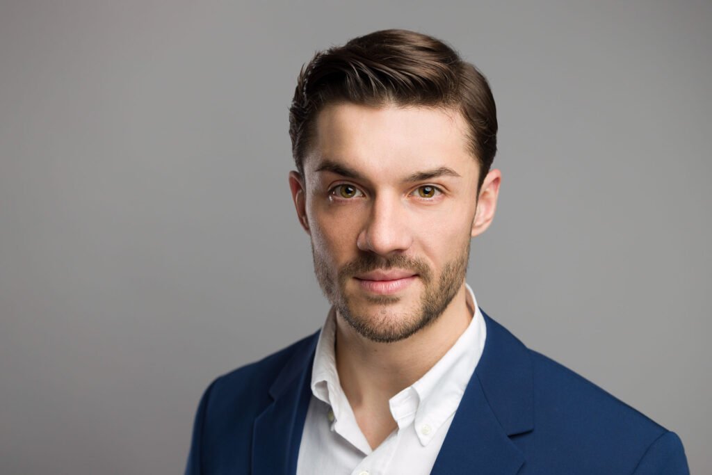Profesjonalny headshot na LinkedIn – portret biznesowy mężczyzny w garniturze na jasnym tle.