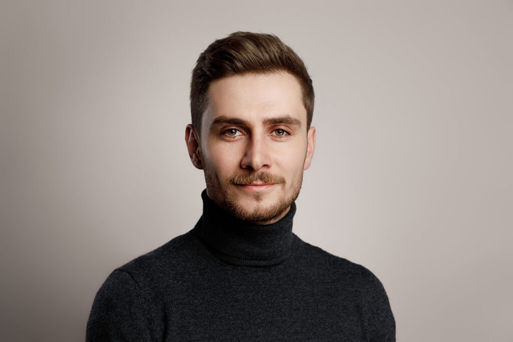 Elegancki portret mężczyzny w ciemnym ubraniu, wykonany w studiu – uwaga skupiona na twarzy i wyrazie