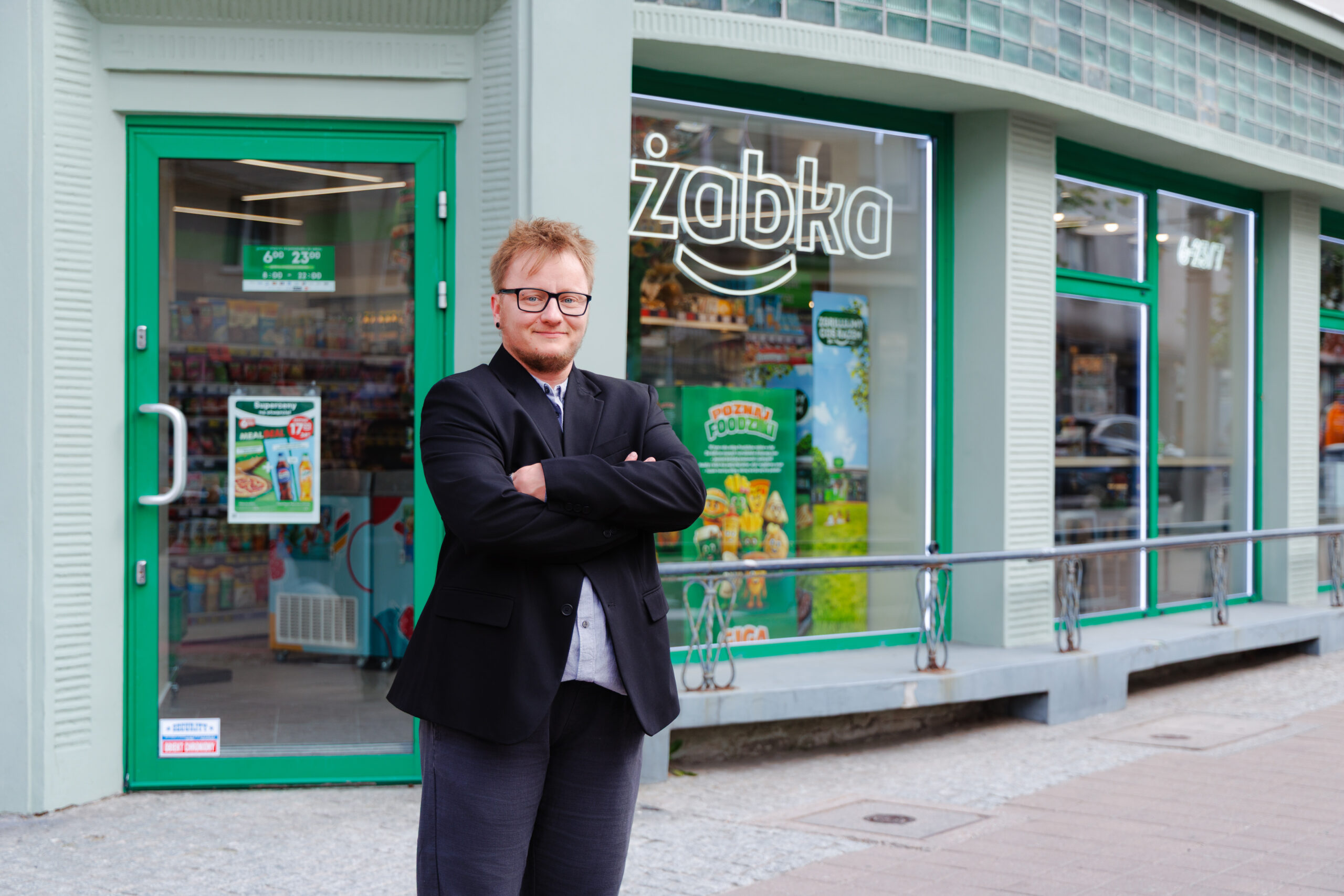 Artur Olszewski proudly posing in front of his Żabka store in Gdynia during a branding photography session