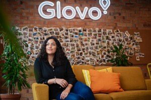 Pracownica z laptopem przed biurem Glovo w Barcelonie podczas sesji biznesowej